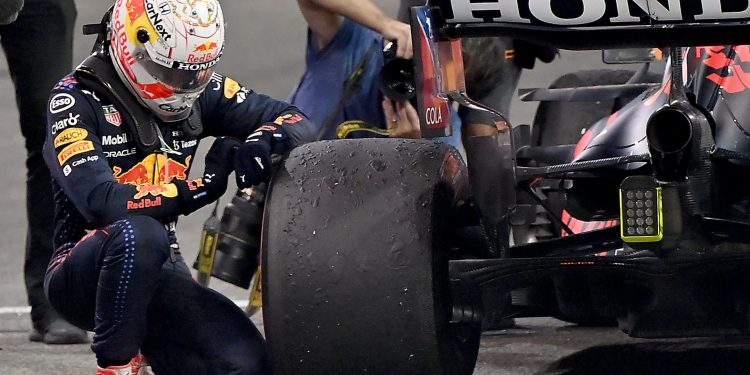 Max Verstappen agachado junto a su Red Bull Honda inspecciona el neumático tras el Gran Premio nocturno de Fórmula 1