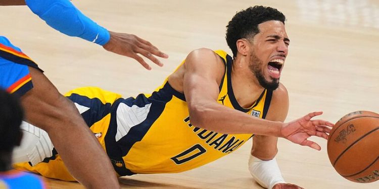 Tyrese Haliburton cae al piso estirando el brazo para alcanzar el balón