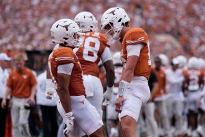 Quarterback y corredor de Texas Longhorns celebran una jugada durante partido colegialTexas Longhorns: Celebración entre quarterback y corredor tras jugada clave