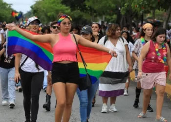 Participantes de la marcha LGBTQ+ en Cancún mostrando banderas de orgullo.