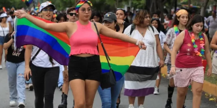 Participantes de la marcha LGBTQ+ en Cancún mostrando banderas de orgullo.