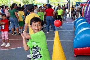  Niño sonriente batea una pelota roja en un juego recreativo dentro de la Carrera Kids por el Agua