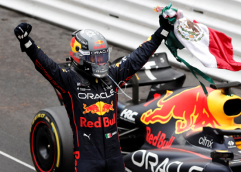 Checo Pérez celebra con bandera de México junto a su auto Red Bull