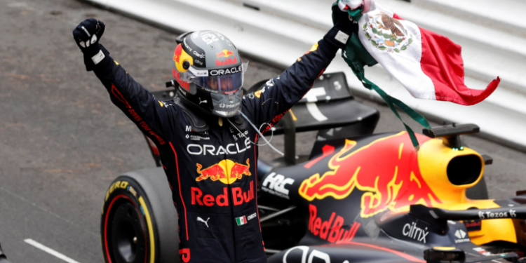 Checo Pérez celebra con bandera de México junto a su auto Red Bull