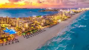 Zona hotelera iluminada frente al mar en Cancún al atardecer