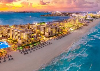 Zona hotelera iluminada frente al mar en Cancún al atardecer