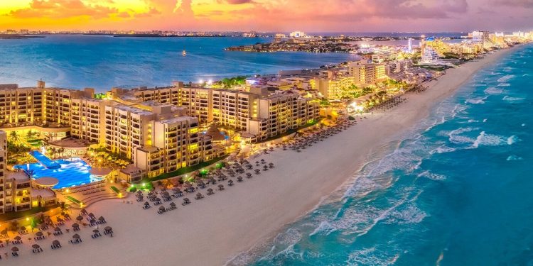 Zona hotelera iluminada frente al mar en Cancún al atardecer
