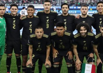 Jugadores de la Selección Mexicana 2025 concentrados en el campo durante un partido amistoso, con el estadio lleno de aficionados.