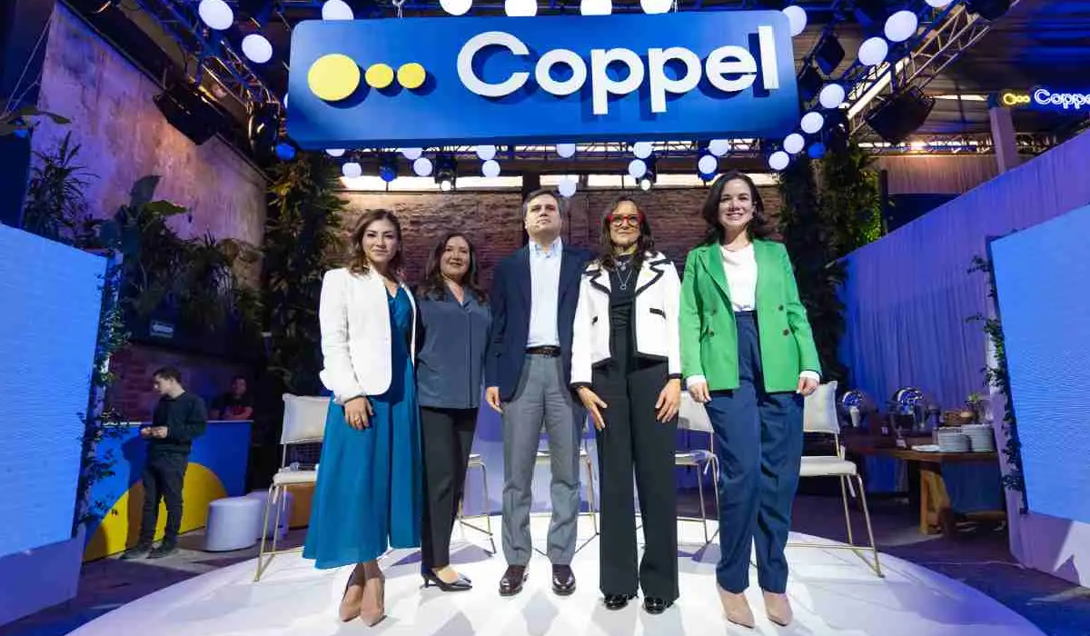 Ejecutivos de Coppel posando bajo el logotipo iluminado en su evento de inversión 2025