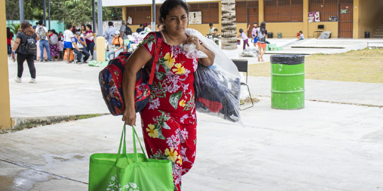 Mujer en Cancún cargando apoyo alimentario de programa social