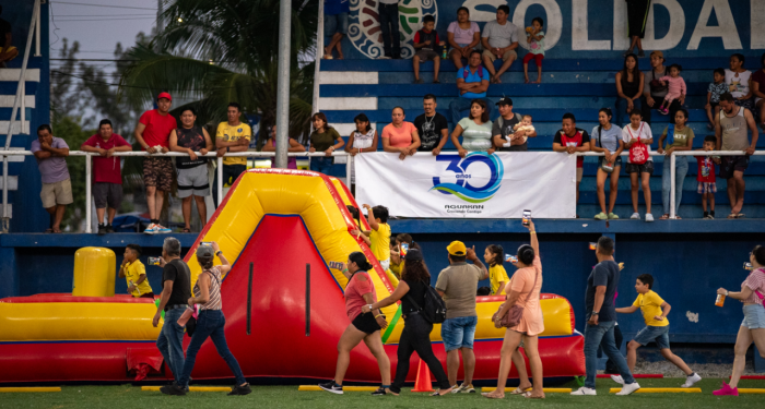 Niños y familias participan junto a un gran castillo inflable en la Carrera Kids por el Agua