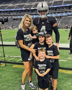 Derek Carr sonríe junto a su esposa e hijos tras un partido de los Raiders en el estadio