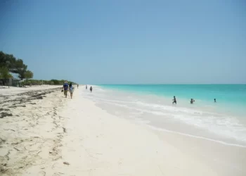 Personas caminando y nadando en playa tranquila de arena blanca en Cancún