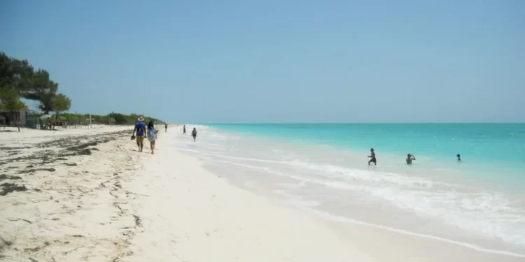 Personas caminando y nadando en playa tranquila de arena blanca en Cancún
