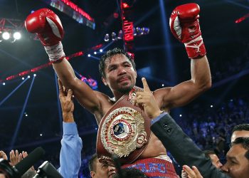 Manny Pacquiao levantando los brazos tras una victoria, con cinturón de campeón welter