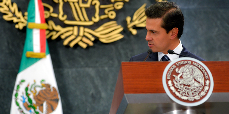 Enrique Peña Nieto con bandera de México de fondo, relacionado con sobornos a Enrique Peña Nieto