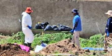 Forenses cargando bolsas con restos humanos en fosa clandestina en Jalisco