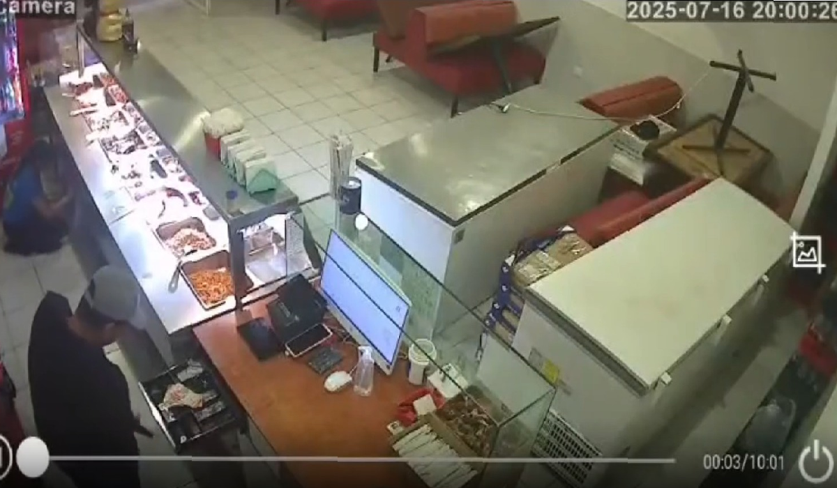 Asaltante abriendo la caja registradora en restaurante