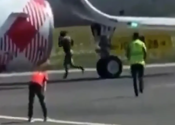 Hombre corriendo cerca del motor de avión en aeropuerto Orio al Serio de Bérgamo