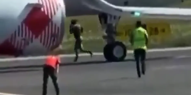Hombre corriendo cerca del motor de avión en aeropuerto Orio al Serio de Bérgamo