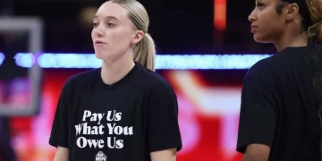Jugadoras de la WNBA con camiseta que dice "Pay Us What You Owe Us"