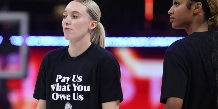 Jugadoras de la WNBA con camiseta que dice "Pay Us What You Owe Us"