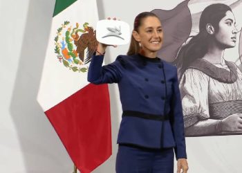 Claudia Sheinbaum mostrando el logo del primer auto eléctrico mexicano
