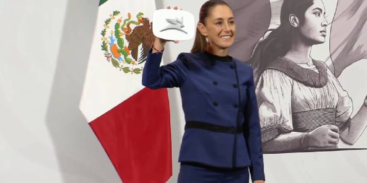 Claudia Sheinbaum mostrando el logo del primer auto eléctrico mexicano