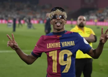 Lamine Yamal celebrando con la camiseta del Barcelona tras un partido, posando para la afición.