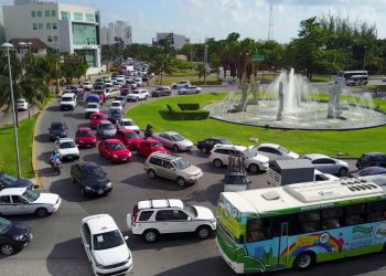 Tráfico intenso en glorieta de Cancún con múltiples vehículos y transporte público
