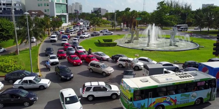 Tráfico intenso en glorieta de Cancún con múltiples vehículos y transporte público