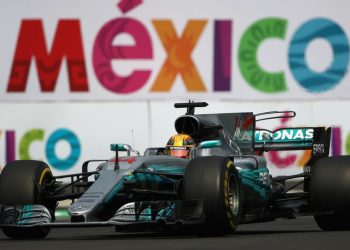 Monoplaza de Fórmula 1 compitiendo en el Autódromo Hermanos Rodríguez con el logo de México al fondo.