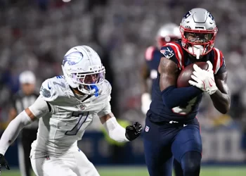 Jugador de los Patriots corre con el balón mientras un defensivo de los Lions intenta detenerlo durante la Semana 5 de la NFL 2025.