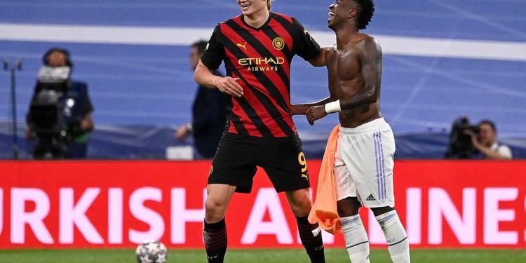 Erling Haaland y Vinicius Jr sonríen juntos en el campo, representando los rumores sobre un posible intercambio entre Real Madrid y Manchester City.