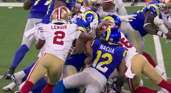 Jugadores de 49ers y Rams en una jugada de fuerza durante partido de NFL 2025.