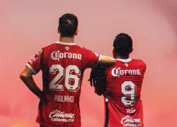 Paulinho y Vega, jugadores del Toluca, de espaldas celebrando con el uniforme rojo.