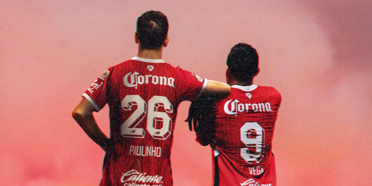 Paulinho y Vega, jugadores del Toluca, de espaldas celebrando con el uniforme rojo.