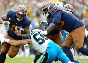 Jugadores de la NFL arrodillados durante el homenaje a Marshawn Kneeland antes del inicio de la Semana 10, con fanáticos aplaudiendo desde las gradas.