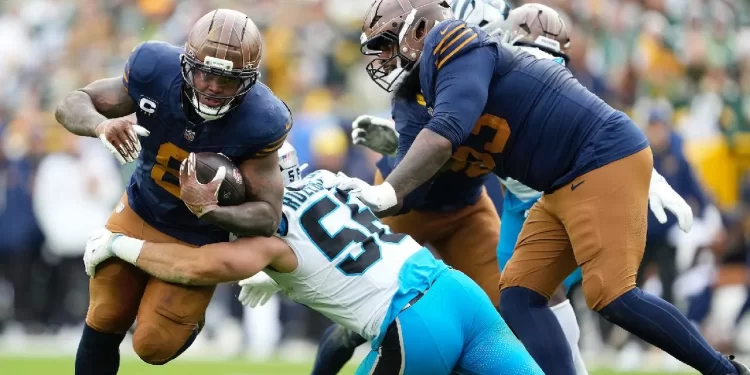 Jugadores de la NFL arrodillados durante el homenaje a Marshawn Kneeland antes del inicio de la Semana 10, con fanáticos aplaudiendo desde las gradas.
