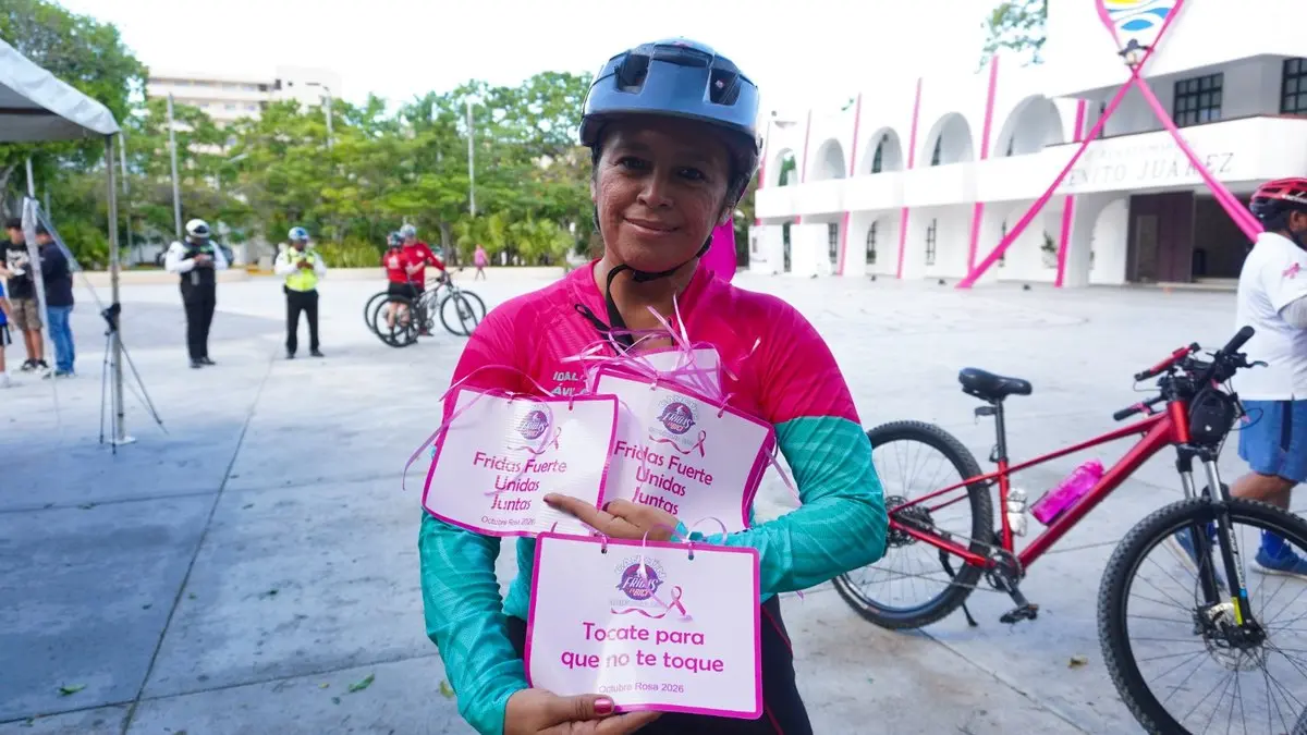 Ciclista con letreros de Octubre Rosa frente al Palacio Municipal de Cancún